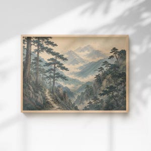 Op de afbeelding: Een rechthoekige ingelijste wandkunstprint met een landschapsschilderij van een bergketen met een kronkelend pad door een bos van hoge dennenbomen. De scène is weergegeven in gedempte tinten groen, bruin en beige met mistige valleien.