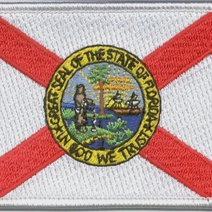 May include: A rectangular embroidered patch featuring the flag of Florida. The design includes a white background with a red saltire cross and the state seal in the center, depicting a person, a palm tree, and a boat with the text IN GOD WE TRUST.