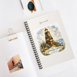 May include: A spiral-bound notebook featuring a cover illustration of a lighthouse constructed from stacked books, surrounded by flowers and birds, with the text The Lighthouse Library and Books are the light that guide me home.