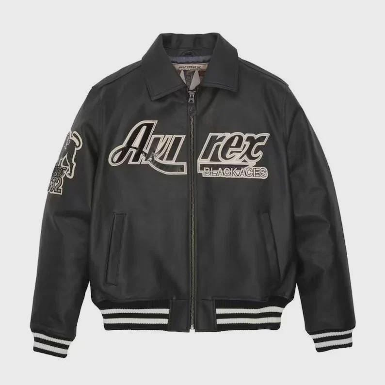 May include: A black leather bomber jacket featuring a full-length front zipper, a classic collar, and ribbed cuffs and hem with white stripes. The chest displays the white embroidered text 'Avirex' and 'BLACK ACES' with a graphic on the sleeve.