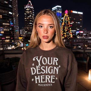 May include: A dark brown crewneck sweatshirt featuring white screen-printed text that reads "YOUR DESIGN HERE" in a stylized serif font, accented by small star icons, with the word "MOCKNOVA" printed in a smaller sans-serif font below.