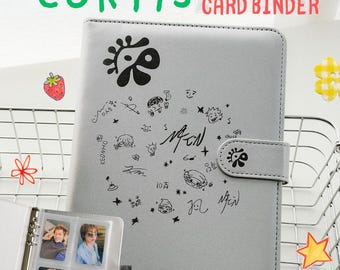 May include: A light gray card binder with a magnetic closure, featuring black ink illustrations and signatures on the front cover. The text CORTIS CARD BINDER is visible at the top. An open page inside displays four small portrait photographs.