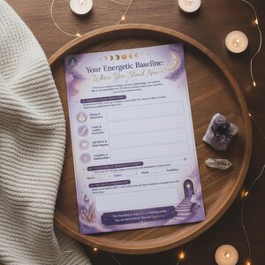 May include: A purple and white printed worksheet titled Your Energetic Baseline: Where You Stand Now, featuring moon phases, a stone archway, and sections for money, career, self-worth, and possibility, resting on a round wooden tray.
