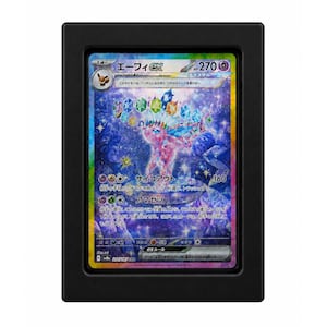May include: A Japanese Espeon ex trading card featuring a pink, crystalline Pokémon with a crown of colorful gems, set against a dark blue, starry background. The card is encased in a rectangular black frame with a clear protective window.