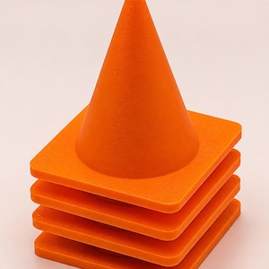 May include: A stack of four bright orange traffic cones. Each cone features a pointed top and a square base with a flat, smooth surface. The cones are nested directly on top of one another, creating a uniform vertical column of orange plastic.