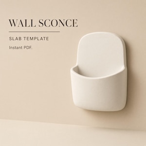 Puede incluir: Una plantilla de losa para aplique de pared con el texto WALL SCONCE SLAB TEMPLATE Instant PDF. El objeto es una forma de pared de color blanco roto mate, redondeada y con forma de bolsillo, con una superficie lisa y sólida y una abertura curva.