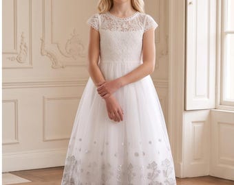 May include: A floor-length white dress featuring a lace bodice with cap sleeves and a round neckline. The skirt is made of tulle and is decorated with a silver floral embroidery pattern along the hemline, which also features a scalloped edge finish.