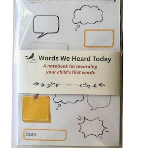 May include: A white notebook titled Words we heard today, wrapped in a paper band with the text Words We Heard Today A notebook for recording your child's first words. The cover features black line art speech bubbles and a yellow sticky note graphic.