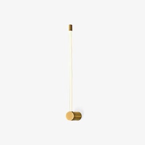 Peut inclure: Une applique murale composée d'une base cylindrique en laiton et d'un long tube en verre vertical et fin qui émet une lueur douce et chaude. Le design est linéaire et vertical, avec un petit capuchon en laiton au sommet de la tige en verre.