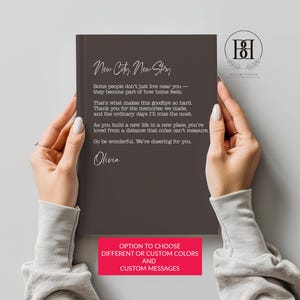 May include: A dark brown hardcover book featuring the white text New City, New Story, followed by a heartfelt farewell message and the name Olivia. The cover design includes a clean, modern layout with elegant script and serif typography.