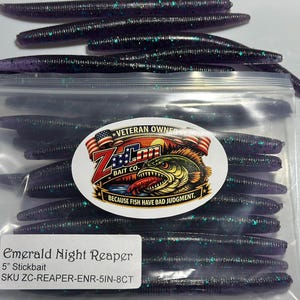 May include: A clear plastic bag containing purple stickbait fishing lures with green glitter flecks. The bag features a Z-Man Bait Co. logo and a label reading Emerald Night Reaper, 5 inch Stickbait, SKU ZC-REAPER-ENR-5IN-8CT.