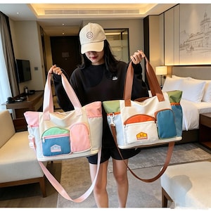 May include: Two large multi-pocket tote bags featuring color-blocked designs. The left bag has pink, light blue, and white panels with a small rectangular patch. The right bag features white, orange, blue, and green panels with a brown strap and patch.