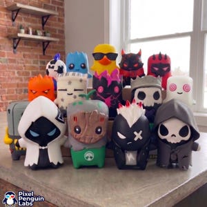 May include: A collection of small, stylised vinyl character figures featuring diverse designs including a yellow duck with sunglasses, a tree-like creature, a skull-faced figure, a hooded character, and various colourful, cartoonish monsters.