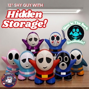 Op de afbeelding: Zeven 30,48 cm Shy Guy-beeldjes met verborgen opbergruimte, in diverse kleuren zoals rood, blauw, paars en roze. Eén figuur draagt een ijshockeymasker en houdt een mes vast. Tekst: 12" SHY GUY WITH HIDDEN STORAGE! en Glow In The Dark Available!