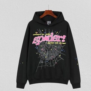 Op de afbeelding: Een zwarte hoodie met een grote afbeelding van een spinnenweb in witte lijnen, geaccentueerd met kleine kleurrijke sterren. De tekst "nevermind the punk, spider!" en "heros the slime" is in roze en geel op de borst gedrukt.
