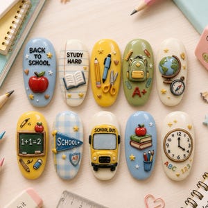 May include: Ten oval-shaped nail art charms featuring school-themed designs including a red apple, a yellow school bus, a globe, a clock, a chalkboard with 1+1=2, books, stationery, and text reading Back to School, Study Hard, and School.