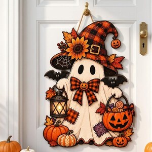 May include: A decorative Halloween door hanger featuring a white ghost wearing a plaid witch hat adorned with a sunflower and autumn leaves. The ghost holds a lit lantern and a pumpkin bucket filled with sweets, surrounded by bats and pumpkins.