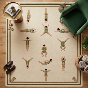 May include: A rectangular area rug with a cream-coloured background and dark green border stripes. The rug features a repeating pattern of figures wearing green swimsuits in various diving and swimming poses, accented with red swim caps.