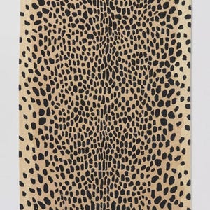 Op de afbeelding: Een rechthoekig vloerkleed met een herhalend zwart dierenprintpatroon op een beige achtergrond. Het ontwerp bestaat uit onregelmatige, langwerpige zwarte vlekken die in het midden dicht op elkaar staan en naar de randen toe minder worden.