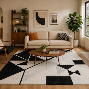 May include: A rectangular area rug featuring a bold geometric pattern in black, white, and shades of gray. The design consists of various triangles, squares, and intersecting lines, creating a high-contrast visual effect across the floor surface.