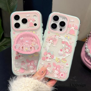 May include: Two clear phone cases featuring a pink and white My Melody character theme with various illustrations of the character, sweets, and strawberries. One case includes a circular pink pop-out grip stand with a small character figure inside.
