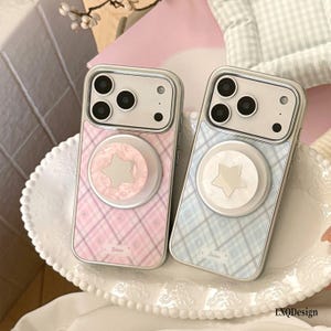 Pode incluir: Duas capas de smartphone com padrão xadrez, uma em rosa e outra em azul claro. Cada capa possui um suporte circular com um centro em forma de estrela. As capas têm uma borda transparente, um recorte para a câmera e o texto "Biane" impresso.