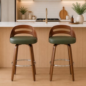 May include: Two swivel bar stools featuring curved walnut-toned wooden backrests with a horizontal cutout, round seats upholstered in dark green faux leather, four tapered wooden legs, and a circular chrome metal footrest connecting the legs.
