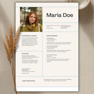 May include: A professional resume template featuring a clean layout with a light beige background, blue grid lines, and a placeholder photo of a person. The document includes sections for professional summary, work experience, education, and core competencies.
