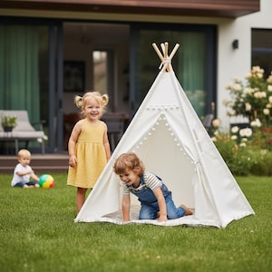 Può includere: Una tenda tipi in tela bianca con pali in legno legati in cima e un bordo decorativo con pompon lungo l'apertura anteriore. La struttura è posizionata su un prato verde, offrendo uno spazio gioco per i bambini che vi entrano.
