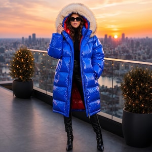May include: A long, glossy royal blue puffer coat featuring a large hood with a thick, cream-coloured faux fur trim. The interior of the hood and the coat lining are bright red. The coat has a front zip closure and a high-shine finish.