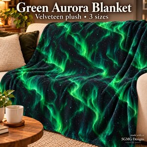 May include: A velveteen plush blanket featuring a vibrant green aurora borealis pattern against a dark starry night sky. The text Green Aurora Blanket and Velveteen plush 3 sizes is printed at the top of the image in a white font.