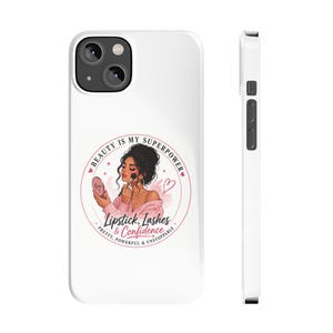 May include: A white smartphone case featuring a circular graphic of a person applying makeup with a brush and mirror. The text reads: Beauty is my superpower, Lipstick, Lashes & Confidence, Pretty, Powerful & Unstoppable. The design includes pink hearts.