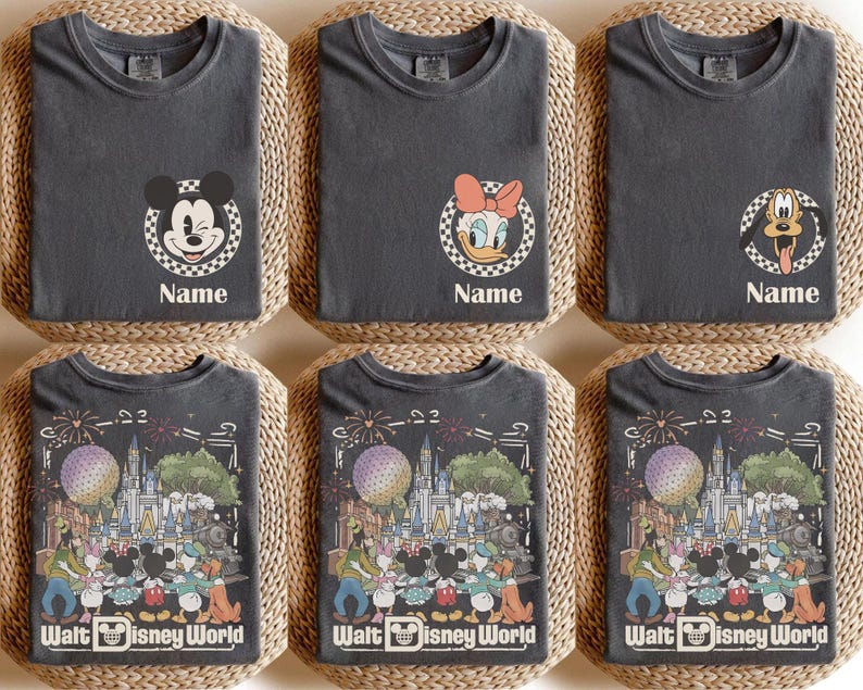 Puede incluir: Una colecci&oacute;n de camisetas gris carb&oacute;n con gr&aacute;ficos de personajes de Disney. El frente muestra un emblema circular a cuadros con Mickey, Daisy o Pluto y el texto Name. La parte posterior muestra una escena detallada del parque Walt Disney World.