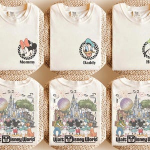 Puede incluir: Seis camisetas de color blanco roto con gr&aacute;ficos de personajes de Disney. Tres camisetas muestran un marco circular a cuadros con Minnie Mouse, el Pato Donald o Goofy y el texto Mommy, Daddy o Henry. Tres camisetas muestran el castillo de Disney.