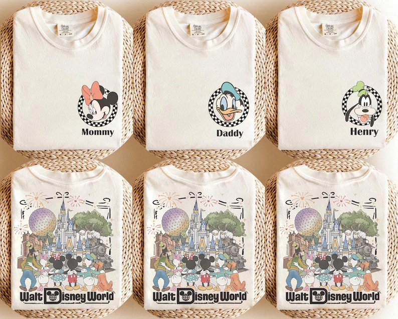 Puede incluir: Seis camisetas de color blanco roto con gr&aacute;ficos de personajes de Disney. Tres camisetas muestran un marco circular a cuadros con Minnie Mouse, el Pato Donald o Goofy y el texto Mommy, Daddy o Henry. Tres camisetas muestran el castillo de Disney.