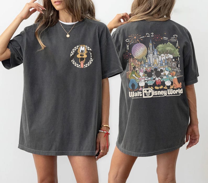 Puede incluir: Una camiseta gris carb&oacute;n de manga corta con un peque&ntilde;o gr&aacute;fico circular de Pluto en el pecho izquierdo. La parte posterior muestra una gran ilustraci&oacute;n colorida de personajes de Disney frente a un castillo con el texto Walt Disney World.