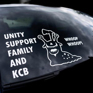 May include: A white vinyl decal applied to a dark car window. The design features a stylized slug holding an axe, with the text "UNITY SUPPORT FAMILY AND KCB" on the left and "WHOOP WHOOP!" on the right, all rendered in a bold, clean white font.