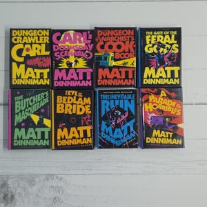 May include: A collection of eight hardcover books by Matt Dinniman, including Dungeon Crawler Carl, Carl's Doomsday Scenario, The Dungeon Anarchist's Cookbook, The Gate of the Feral Gods, The Butcher's Masquerade, The Eye of the Bedlam Bride, This Inevitable Ruin, and A Parade of Horribles.