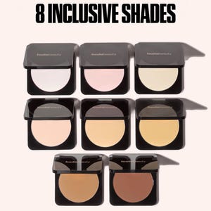 May include: Eight square black compacts of Huda Beauty face powder arranged in three rows. The text 8 INCLUSIVE SHADES appears at the top. Each compact features a circular pan of pressed powder in varying skin tone shades from light to dark.