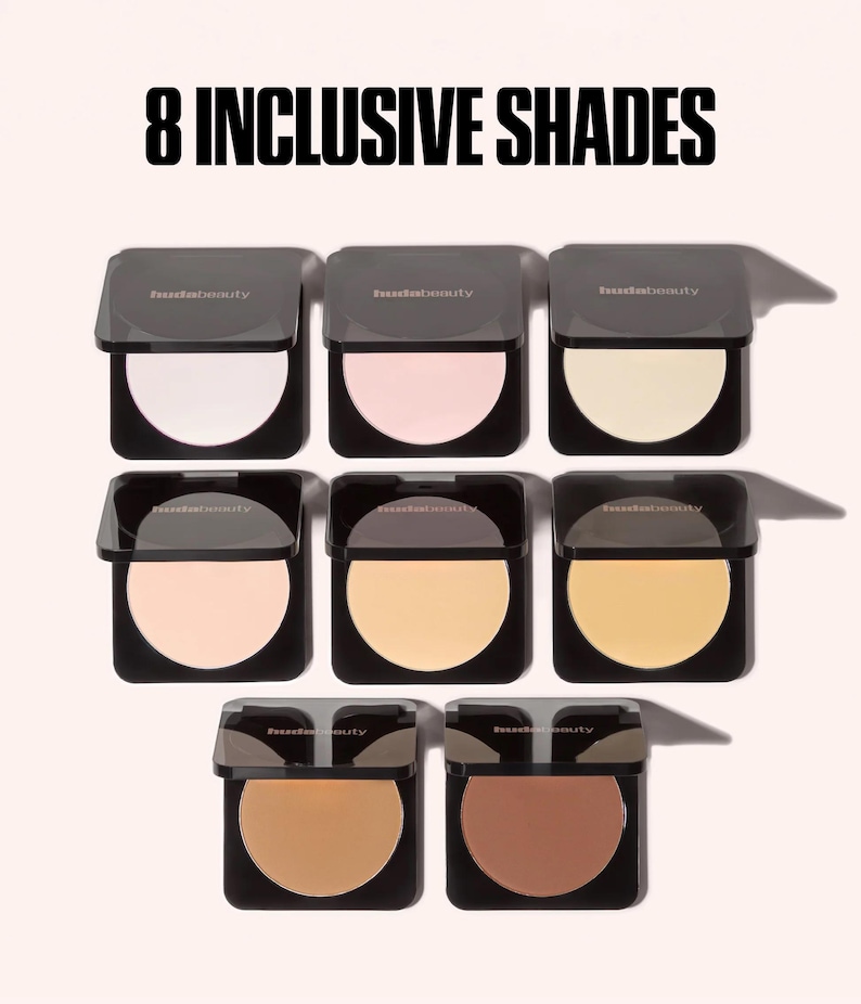 May include: Eight square black compacts of Huda Beauty face powder arranged in three rows. The text 8 INCLUSIVE SHADES appears at the top. Each compact features a circular pan of pressed powder in varying skin tone shades from light to dark.