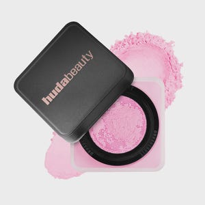 May include: A square cosmetic container with a black lid featuring the text hudabeauty in light pink. The base is light pink with a black circular insert containing a fine, bright pink loose powder visible through a mesh sifter screen.