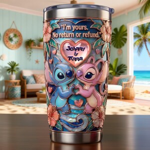 May include: A stainless steel tumbler featuring a blue and pink alien character design with hibiscus flowers and a heart. The text reads, "I'm yours. No return or refund." and "Johnny & Anna" inside a central heart. The finish has a stained glass effect.