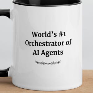 Könnte beinhalten: Ein weißer Keramikbecher mit schwarzem Henkel und schwarzem Innenrand. Auf der Vorderseite steht in schwarzer Schrift World's #1 Orchestrator of AI Agents, zentriert über einer kleinen, einfachen schwarzen Grafik aus zwei symmetrischen Zweigen.