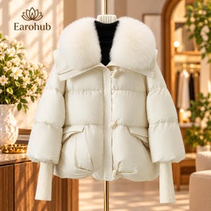 Könnte beinhalten: Eine weiße Daunenjacke mit einem großen, flauschigen weißen Kunstfellkragen, langen Ärmeln mit gerippten Strickbündchen und einem Vorderverschluss mit Knebelknöpfen. Die Jacke hat ein gestepptes Design mit zwei Vordertaschen und einem schwarzen Rollkragen.