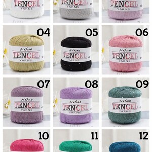 May include: A collection of twelve cylindrical yarn skeins in various colors, each wrapped in a white paper band labeled Nihao TENCEL YARNS. The yarn colors include white, gray, pink, gold, black, rose, purple, lavender, teal, magenta, green, and blue.