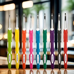 Könnte beinhalten: Ein Set aus neun Häkelnadeln mit metallisch silbernen Spitzen und ergonomischen Griffen in Limettengrün, Gelb, Orange, Pink, Blau, Grün, Lila, Schwarz und Rot. Jeder Griff trägt eine Buchstaben- und metrische Größenangabe von 2,0mm bis 6,0mm.