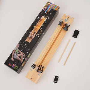 May include: A wooden paracord bracelet jig with a built-in ruler, featuring black plastic side-release buckles at both ends. The set includes two wooden dowels and an extra buckle, all packaged in a black box with a graphic of a person crafting.