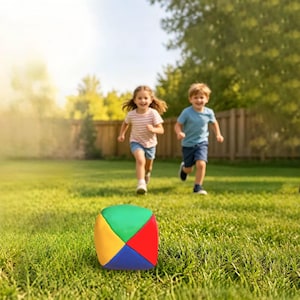May include: A soft, multi-colored fabric ball featuring triangular panels in vibrant shades of green, red, yellow, and blue. The ball is shaped like a cube with rounded edges and sits on a green lawn, showcasing a smooth, plush texture.