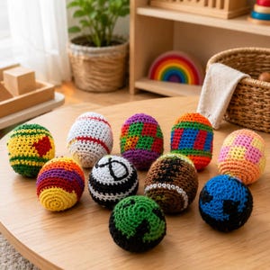 Op de afbeelding: Een verzameling van tien kleine, ronde, gehaakte garenballen in diverse kleuren en patronen, waaronder groen met geel, wit met rode strepen, paars met groen geblokt, oranje met blauw, en zwart-witte ontwerpen.