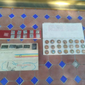 May include: A collection of three sets of vintage pins displayed on cardboard backing. One set features square pins on a red background, another has rectangular pins on a white card with the text VOLGOGRAD, and the third has round pins on a white card.